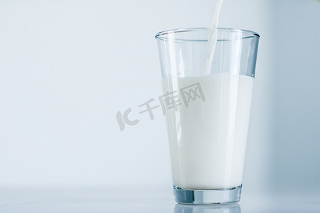 世界牛奶日，倒入大理石桌上的玻璃杯中
