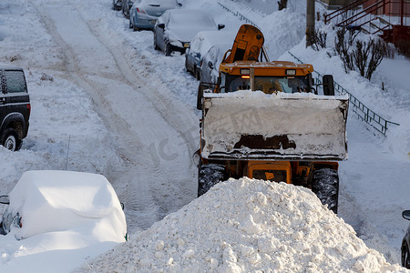 拖拉机在冬日从住宅楼附近的停车场除雪