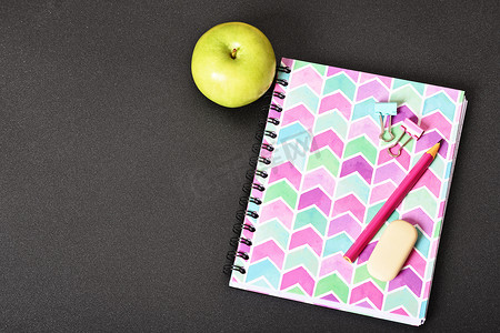 黑色背景中的粉色笔记本和苹果