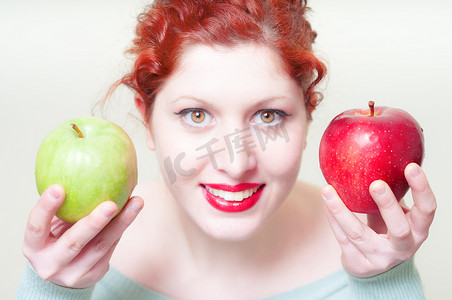 美丽的红头发和嘴唇女孩与绿色和红色的苹果