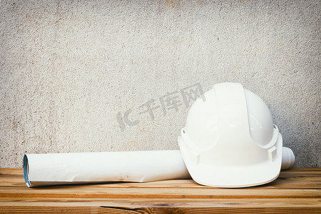 白色安全头盔塑料和纸卷计划工程蓝图施工在木地板桌子背景上带复制空间添加文本