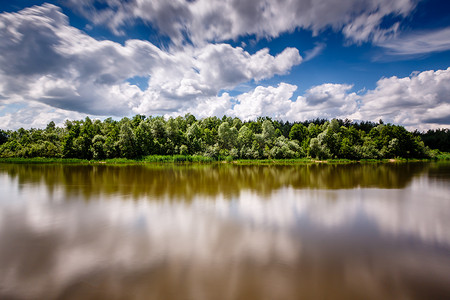 变化的云摄影照片_多云的天空和莫斯科附近的河流之间的森林条纹，V