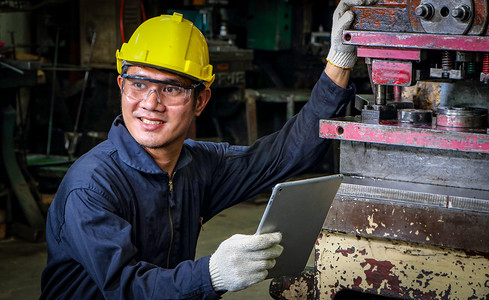 熟练的亚洲工人穿着统一的服装、安全帽和护目镜。