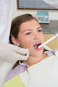 儿科牙医在牙医椅上检查小女孩的牙齿
