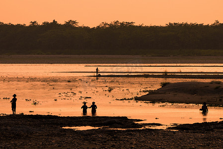 亚洲女性在河里钓鱼，夕阳下的剪影