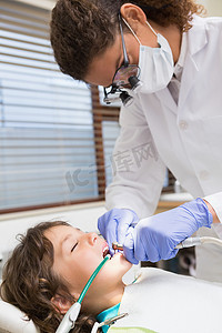 儿科牙医在牙医椅上检查小男孩的牙齿