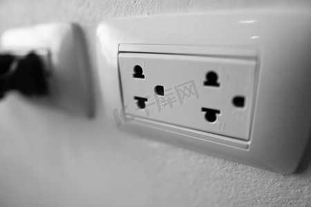 通用电气摄影照片_白墙上的白色通用电源插座插头。
