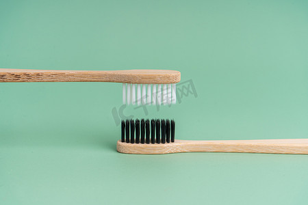 浅绿色背景上有白色和黑色刷毛的两把环保抗菌竹木牙刷。