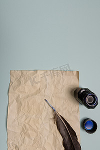 墨水瓶羽毛笔摄影照片_红色背景上的乌鸦羽毛、墨水瓶和旧黄纸。