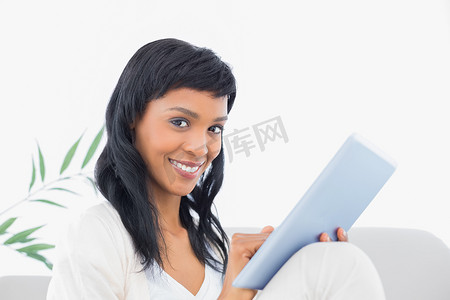 穿着白色衣服的黑发女人在平板电脑上打字很高兴