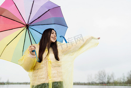 美丽的黑发女人在雨中撑着五颜六色的雨伞