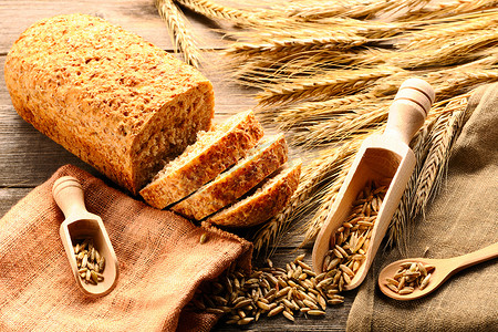 木质背景中的黑麦小穗和切片面包