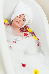 正在营业摄影照片_放松的女人，头上戴着毛巾，正在放松地洗澡