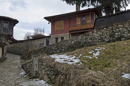 古代屋檐摄影照片_Koprivshtitsa 以其鹅卵石街道而独特的小镇，涂有明亮色彩的房屋，带有阳台和风景如画的屋檐