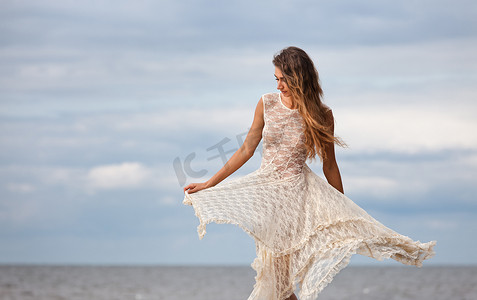 穿着半透明裙子的女孩背对着大海