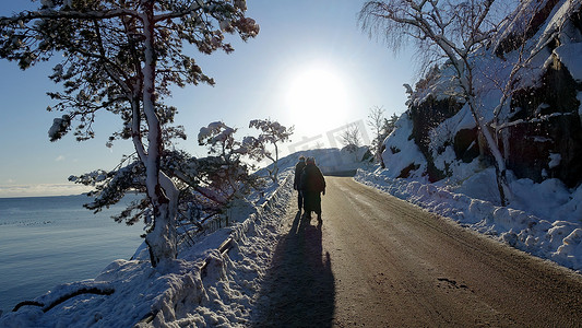 阳光照在一条雪街上，两个人在冬日的早晨漫步
