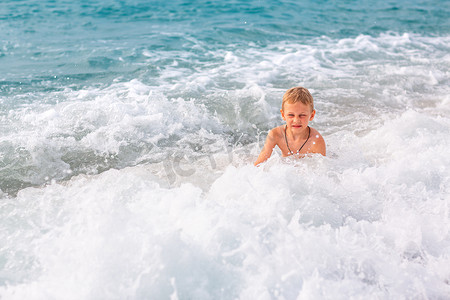 快乐的小男孩在海边的海浪中玩得开心
