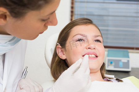 儿科牙医在牙医椅上检查小女孩的牙齿