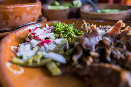 粘土碗中的墨西哥碎羊肉、辣酱和酸橙片