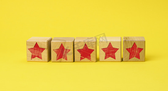 黄色背景上带有红色星星的五个木制立方体。