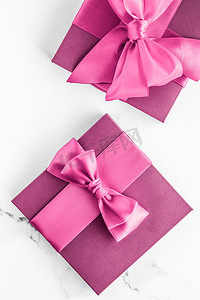 礼盒展示摄影照片_大理石背景上带丝绸蝴蝶结的粉红色礼盒、女婴淋浴礼物和奢华美容品牌的魅力时尚礼物、假日平板艺术设计