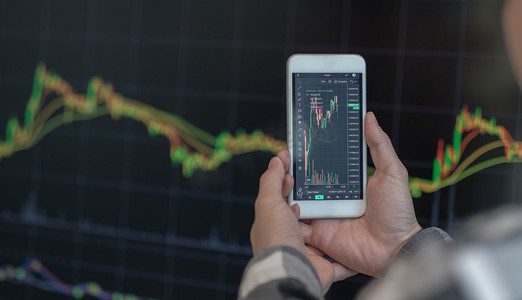 商人交易员投资者分析师使用手机应用程序分析进行加密货币金融股市分析，分析智能手机屏幕上的图表交易数据指数投资增长图表。