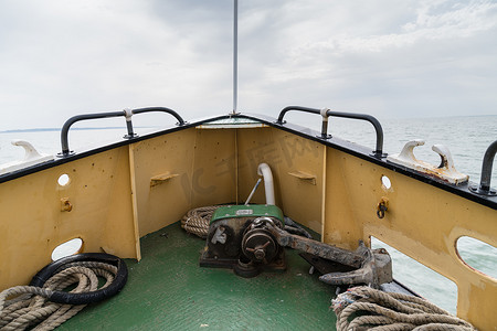 从英国恩格朗的泰晤士河口航行的机动船的船头可以看到远处的大海和地平线，甲板上有锚和绳索