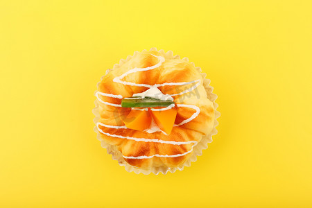 黄色背景简单摄影照片_黄色背景下带桃子、猕猴桃和奶油的纸杯蛋糕的顶部视图