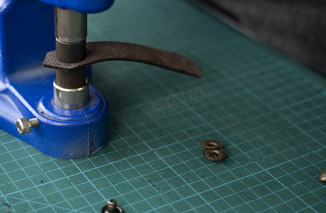 工匠使用手压机在皮革上设置按扣以制作钱包。