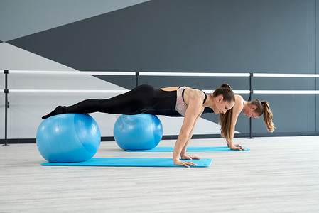 女性使用健身球练习平板支撑姿势。