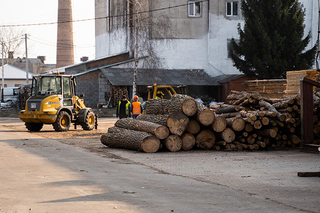 May摄影照片_LUTSK, UKRAINE - May 10, 2020：黄色轮式装载机挖掘机在锯木厂工作。
