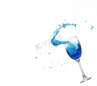 在白色背景的酒杯丝毫蓝色水飞溅。