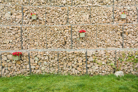 石笼围墙由钢丝网制成，用石头装饰花朵。