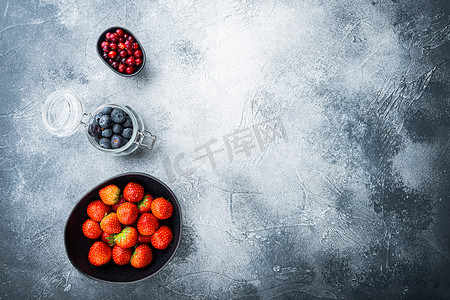 蓝色文字纹理摄影照片_成熟的草莓、蔓越莓和蓝莓放在碗里，顶视图有文字空间，有纹理的背景
