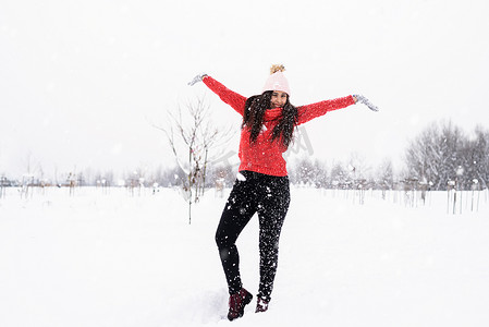 穿着红色毛衣的黑发年轻女子在公园里玩雪