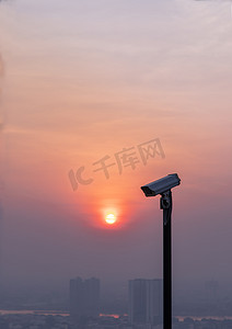 在都市风景和摩天大楼背景的现代监控照相机与太阳在太阳落山前闪耀。