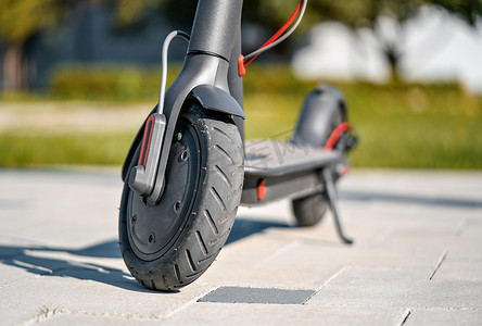 停在瓷砖石路面上的电动滑板车 — 前轮的特写细节