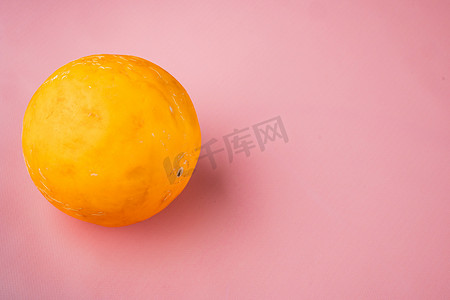 质感背景粉色摄影照片_整个黄色熟瓜，在粉红色质感的夏季背景中，带有文本复制空间
