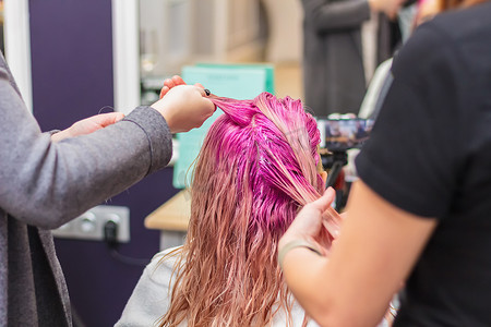 在美容院给女孩子染发，长发粉色。