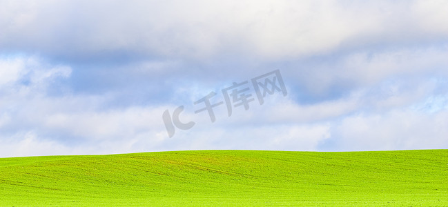 蓝天白云背景摄影照片_山上的绿草地和乡村的蓝天白云。