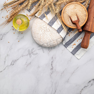 擀面杖摄影照片_基于麦穗和擀面杖的大理石桌上的新鲜自制酵母面团。