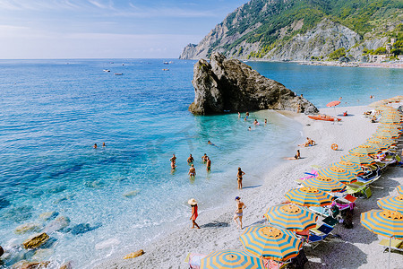 椅子和遮阳伞填满了 spiaggia di fegina 海滩，这是意大利 Monterosso 宽阔的沙滩村，是意大利五渔村的一部分