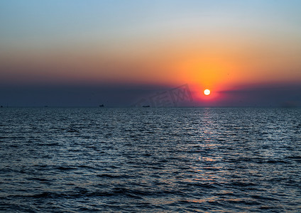 蓝色大气摄影照片_美丽的夕阳在平静的海面与蓝色和橙色的发光天空。