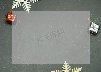 金色名片摄影照片_优雅的圣诞背景复制空间，金色雪花和铃铛，闪亮的礼盒，黑色木质背景。