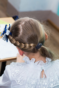 一个女孩的发型，头上扎着辫子，特写是蓝色的蝴蝶结。