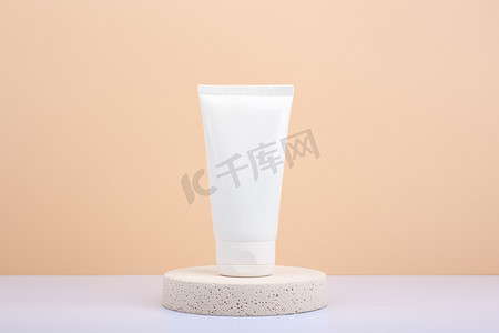 米色磨砂背景摄影照片_圆形米色讲台上的护手霜、乳液或磨砂膏，米色背景，带复制空间。