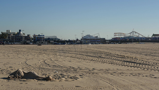 美国加利福尼亚州洛杉矶圣塔莫尼卡 — 2019 年 12 月 19 日，孤独的匿名男子看起来像是失业和无家可归的人，睡在沙滩上。