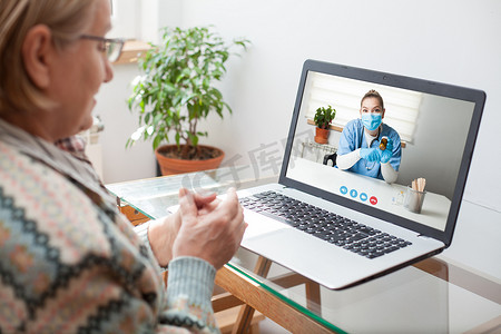 关怀热线摄影照片_年轻女医生通过视频帮助热线虚拟医疗预约咨询老年妇女