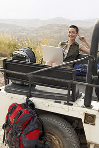 沙漠肖像中坐在四轮驱动汽车后面使用笔记本电脑的女性
