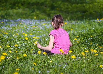 绿色春天草地上的一个女孩，阳光下有很多野花。